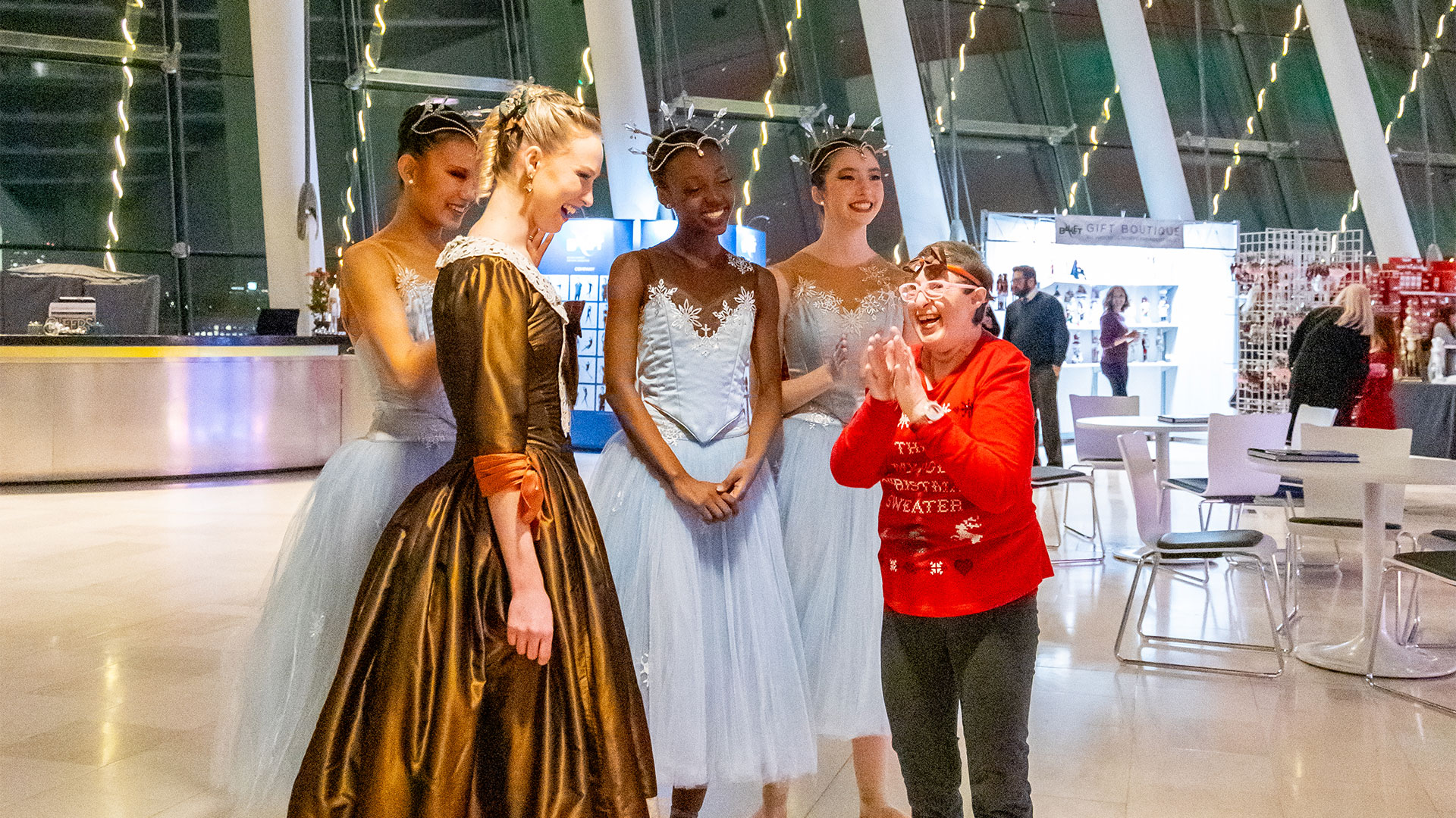 A person stands with dancers in blue and brown costumes.